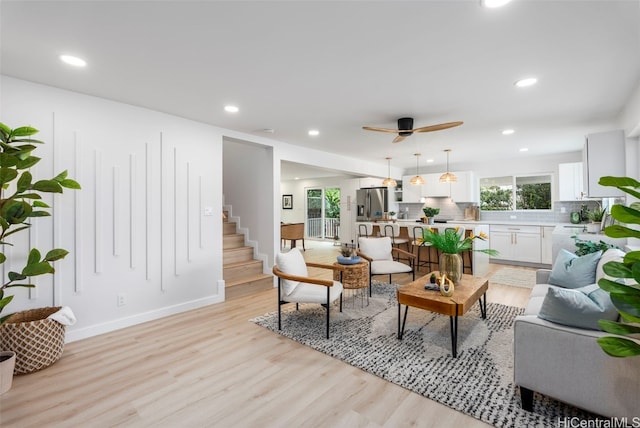 living room with stairs, light wood finished floors, and recessed lighting