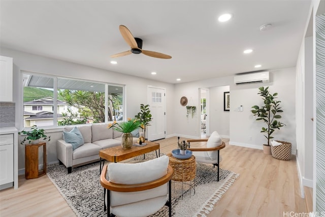 living area with recessed lighting, a wall unit AC, light wood-style flooring, and baseboards