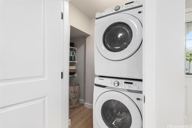 laundry area featuring stacked washer and clothes dryer, light wood finished floors, and laundry area