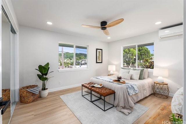 bedroom with light wood-style floors, recessed lighting, multiple windows, and a wall mounted air conditioner