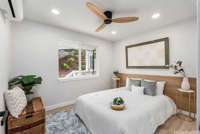 bedroom featuring baseboards, a wall unit AC, ceiling fan, light wood-style floors, and recessed lighting