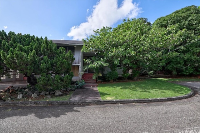 view of property hidden behind natural elements featuring a front lawn