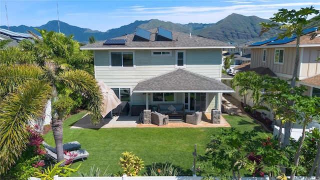 back of house featuring an outdoor living space, a patio, a mountain view, and a lawn
