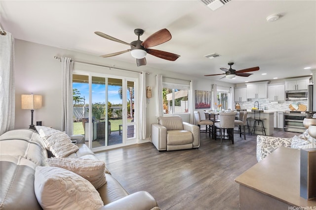 living room with visible vents, ceiling fan, and dark wood finished floors