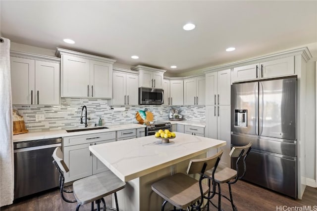 kitchen with tasteful backsplash, a sink, a breakfast bar, dark wood-style floors, and stainless steel appliances