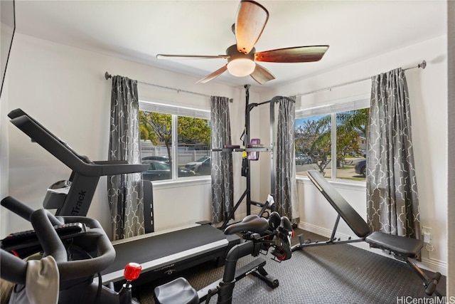 exercise area featuring baseboards, a ceiling fan, and a wealth of natural light