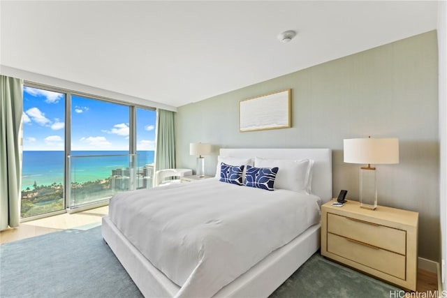 bedroom with floor to ceiling windows, a water view, and access to outside