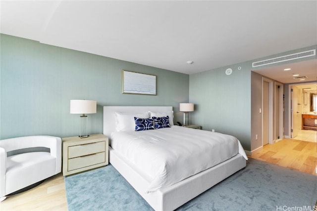 bedroom featuring visible vents, connected bathroom, and wood finished floors