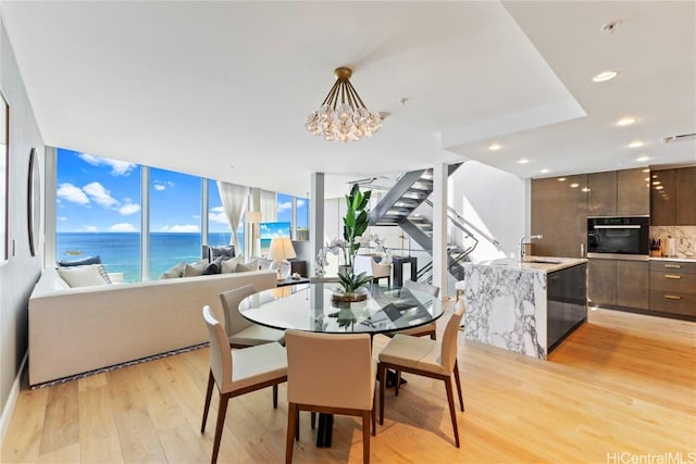 dining space featuring recessed lighting, light wood-type flooring, a water view, and a chandelier