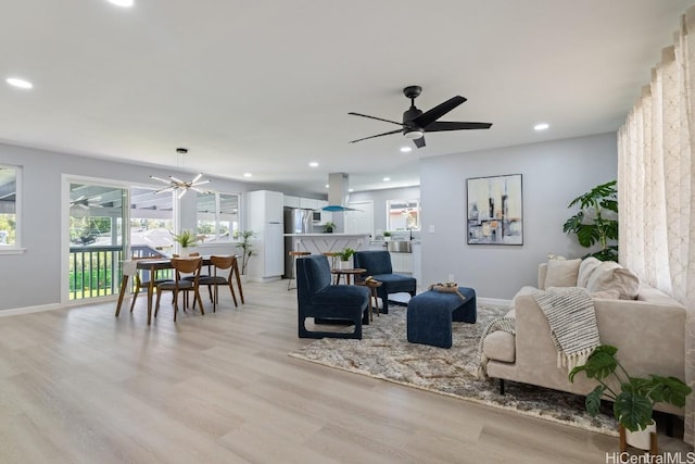 living room featuring light wood-style floors, recessed lighting, ceiling fan, and baseboards