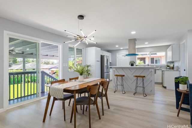 dining space with light wood-type flooring, a notable chandelier, and recessed lighting