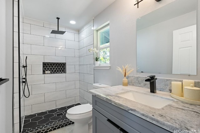 full bath with tiled shower, vanity, and toilet