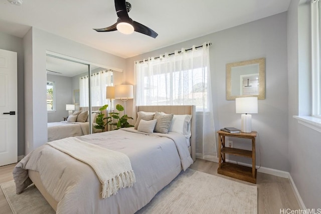 bedroom with light wood-style floors, a closet, multiple windows, and baseboards