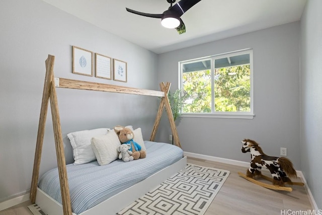 bedroom with light wood-type flooring, ceiling fan, and baseboards