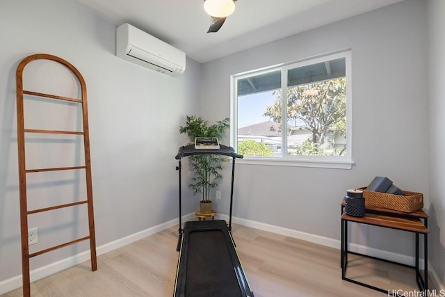 workout area featuring light wood-style floors, baseboards, and a wall mounted air conditioner