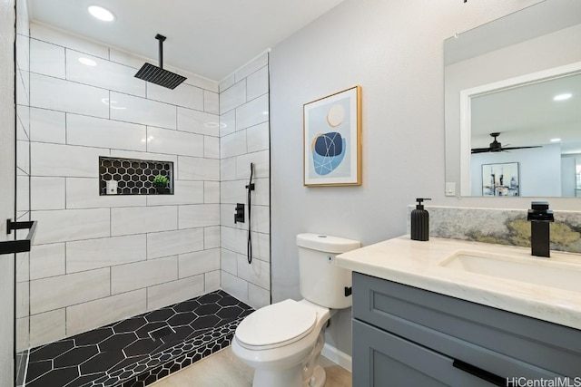 bathroom featuring toilet, a tile shower, vanity, and recessed lighting