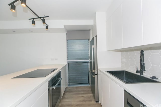 kitchen with tasteful backsplash, light wood-style flooring, appliances with stainless steel finishes, white cabinetry, and a sink