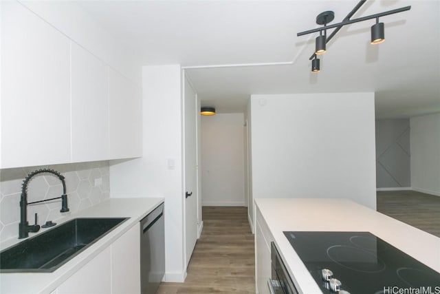 kitchen featuring electric stovetop, white cabinetry, stainless steel dishwasher, and a sink