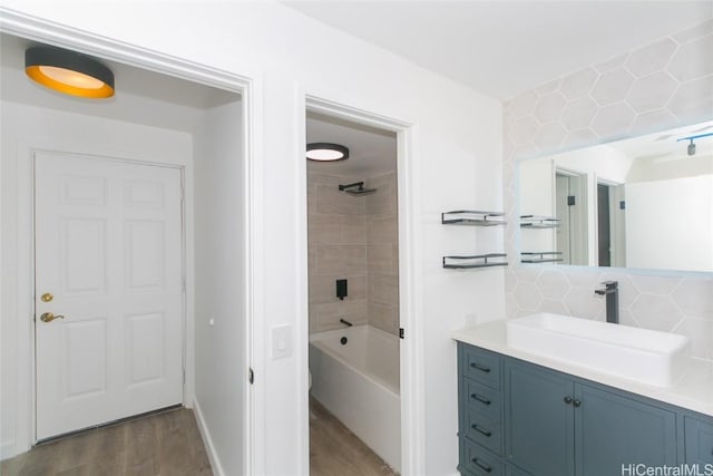 full bath with tasteful backsplash, washtub / shower combination, wood finished floors, and vanity