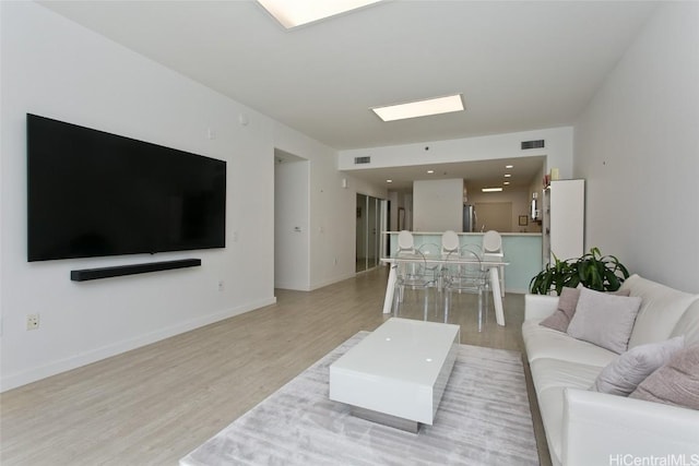 living area with wood finished floors, visible vents, and baseboards