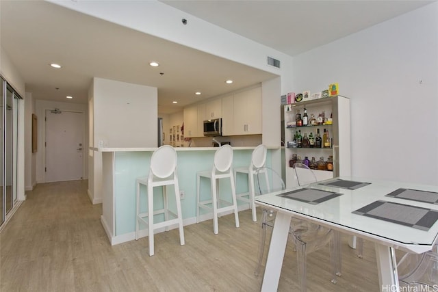 kitchen with stainless steel microwave, light wood-type flooring, and recessed lighting