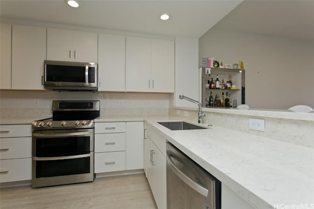 kitchen featuring stainless steel appliances, recessed lighting, light wood-style flooring, white cabinetry, and a sink