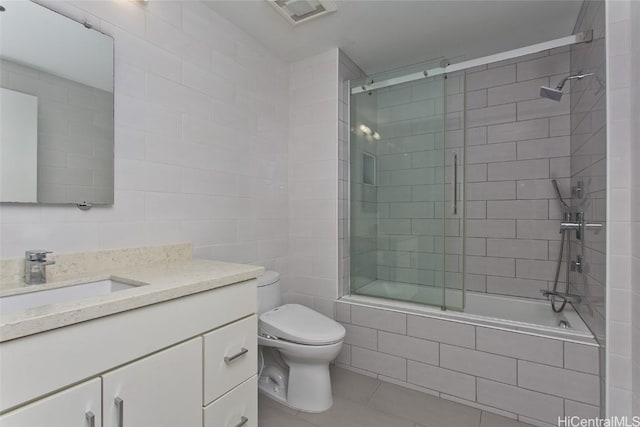 bathroom featuring visible vents, toilet, tile patterned floors, tiled shower / bath, and vanity