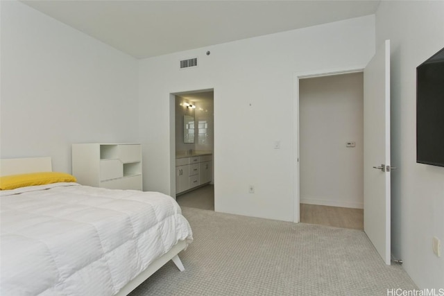 bedroom with visible vents, ensuite bath, and carpet flooring