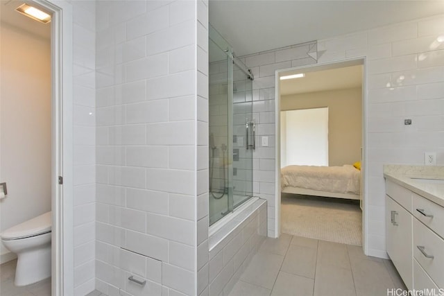 ensuite bathroom with tiled shower, toilet, ensuite bath, tile patterned floors, and vanity