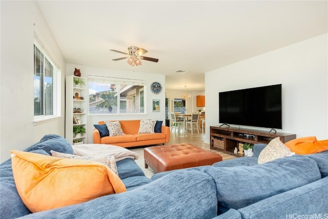 living area featuring ceiling fan with notable chandelier