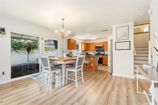 dining area featuring baseboards, light wood-style floors, an inviting chandelier, and stairs