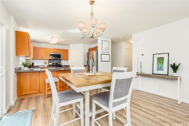 dining space featuring baseboards, light wood-type flooring, and an inviting chandelier