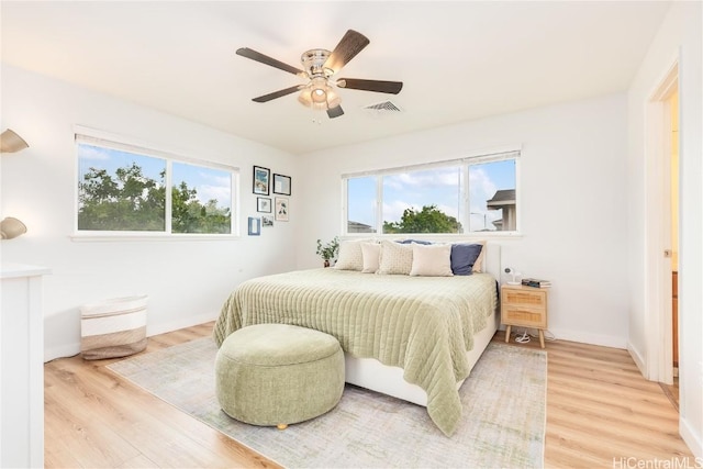 bedroom featuring multiple windows, light wood-style floors, visible vents, and baseboards