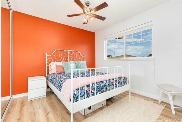 bedroom featuring baseboards, wood finished floors, and a ceiling fan