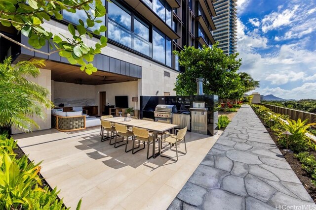 view of patio featuring area for grilling, ceiling fan, outdoor dining space, and an outdoor kitchen