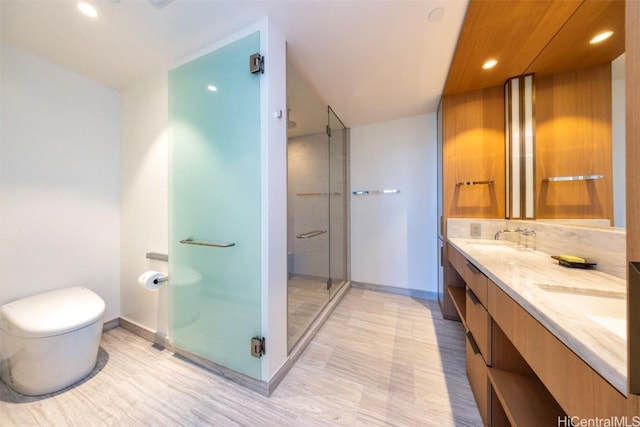 bathroom featuring toilet, a sink, baseboards, a shower stall, and double vanity