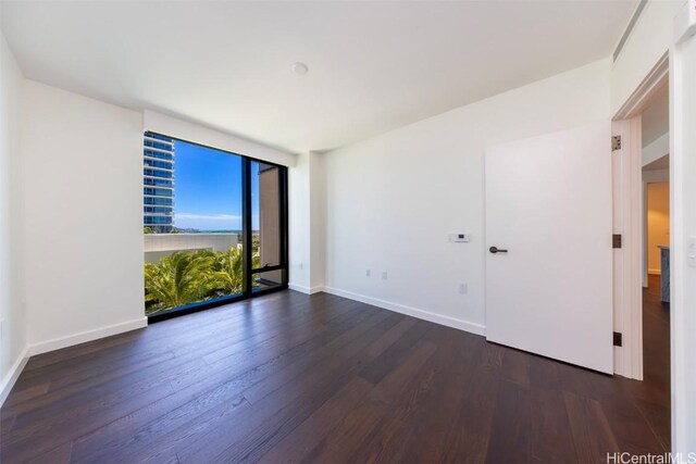 empty room with expansive windows, dark wood-type flooring, and baseboards