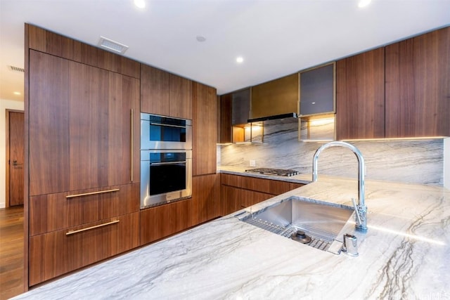 kitchen featuring brown cabinets, visible vents, appliances with stainless steel finishes, a sink, and modern cabinets