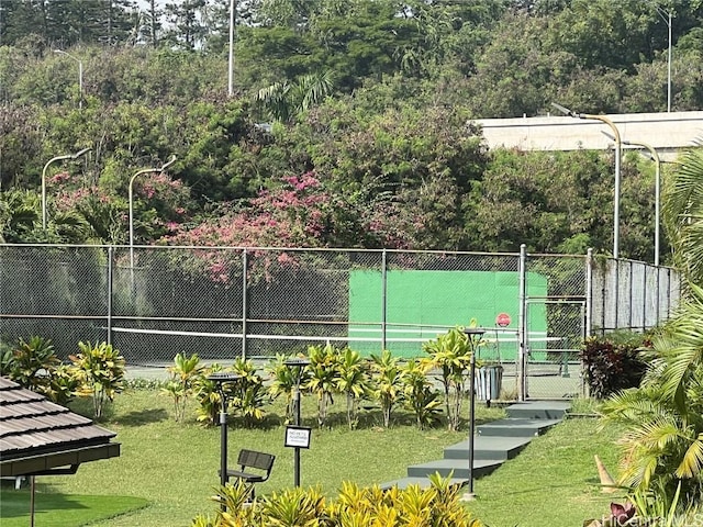 view of tennis court with a lawn, fence, and a gate