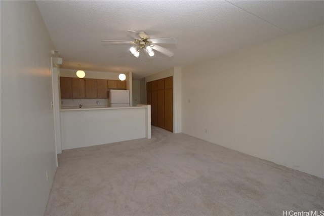 unfurnished living room with a textured ceiling, a ceiling fan, and light colored carpet