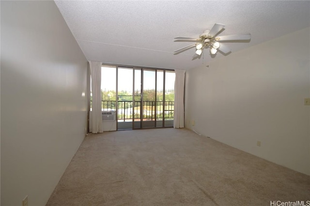 spare room with a textured ceiling, ceiling fan, a wall of windows, and light colored carpet