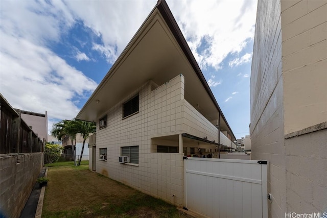 view of home's exterior with cooling unit, concrete block siding, and fence