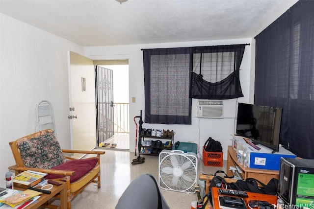 interior space with cooling unit, concrete block wall, a textured ceiling, and speckled floor