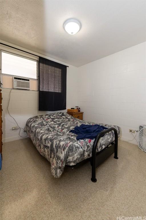 bedroom with cooling unit and concrete block wall