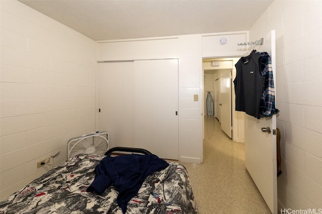 bedroom featuring concrete block wall and a closet