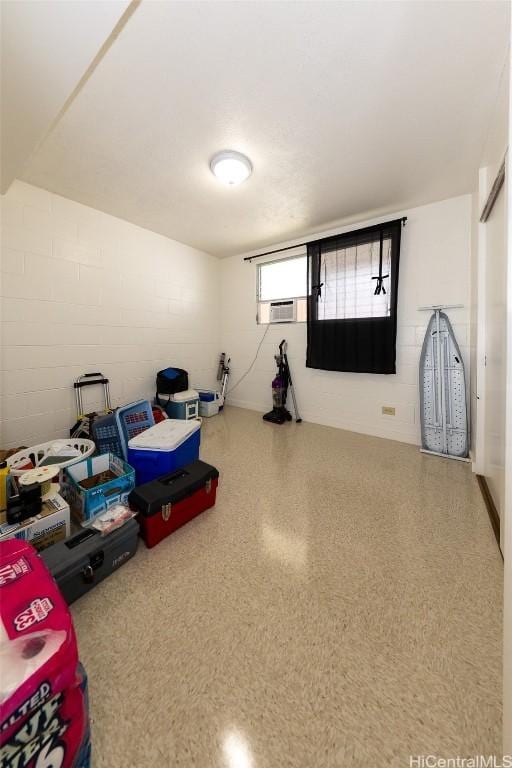 playroom featuring speckled floor and concrete block wall