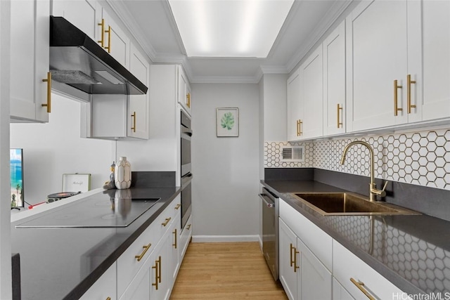 kitchen with under cabinet range hood, a sink, dark countertops, white cabinetry, and appliances with stainless steel finishes