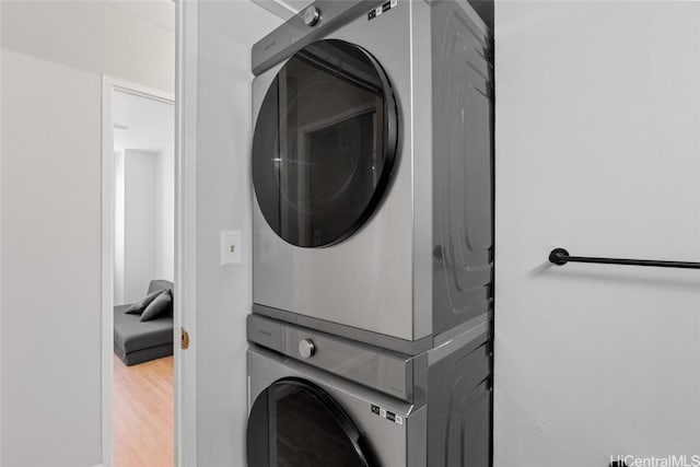 laundry room featuring laundry area, wood finished floors, and stacked washing maching and dryer