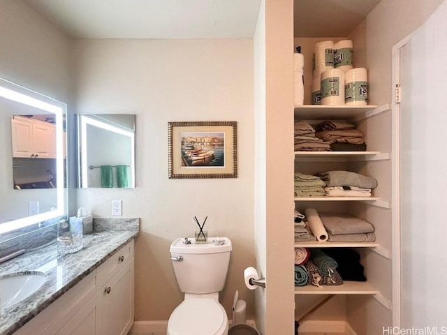 bathroom featuring toilet, a closet, and vanity