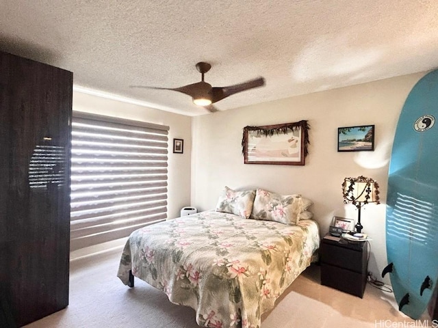 bedroom with a ceiling fan, light colored carpet, and a textured ceiling